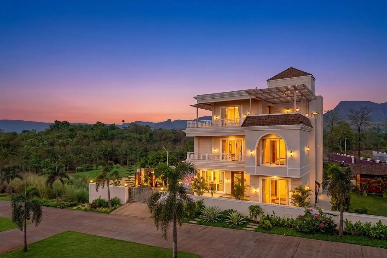 The villa lit at dusk, seen from the drive